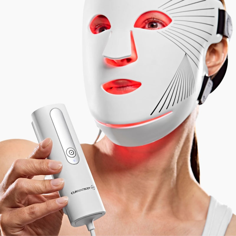 Donna che indossa la maschera LED viso Currentbody e mostra il telecomando